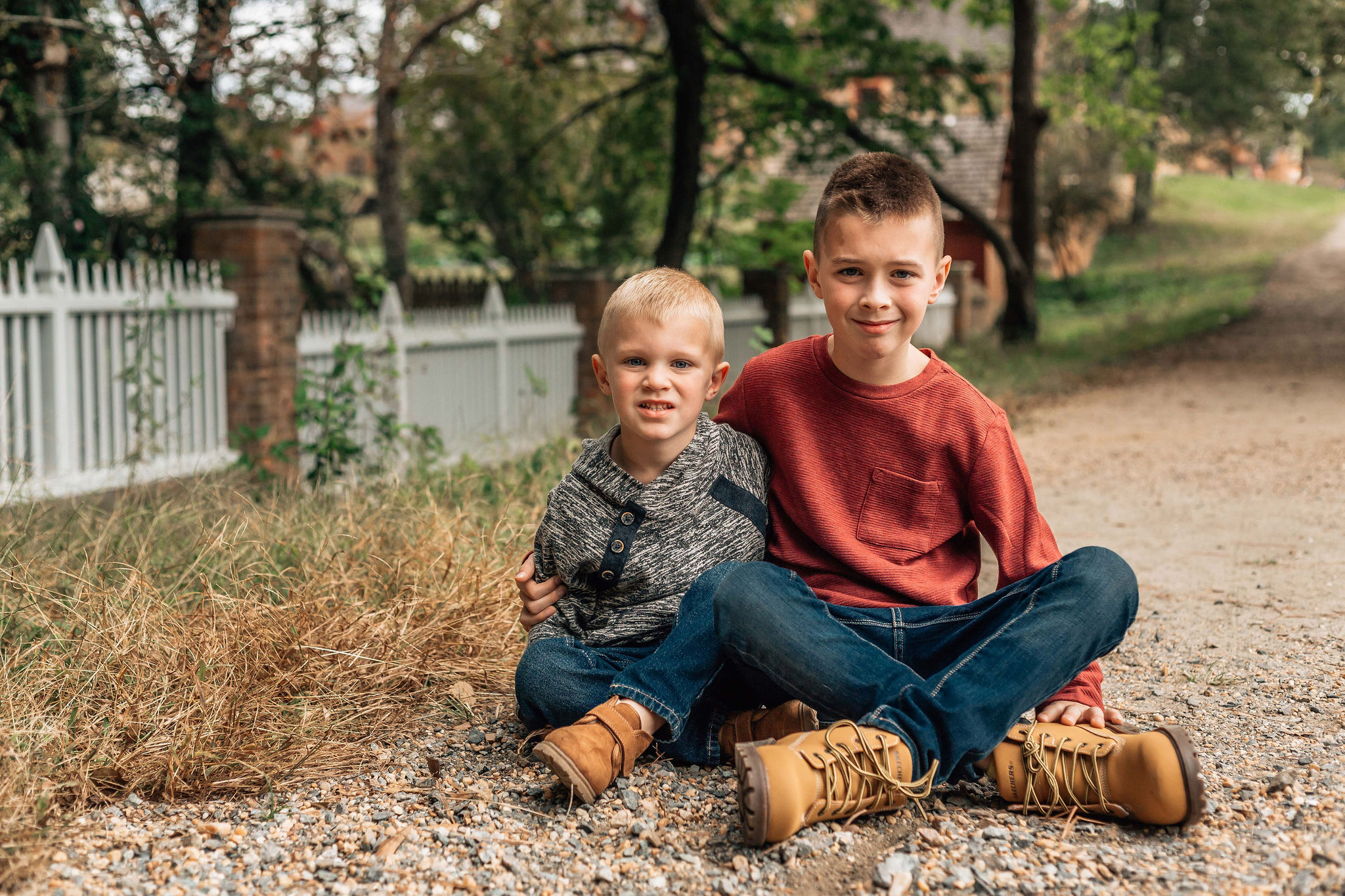 two brothers sitting together with their arms around each other and smiling captured by Hampton Roads Family Photographer