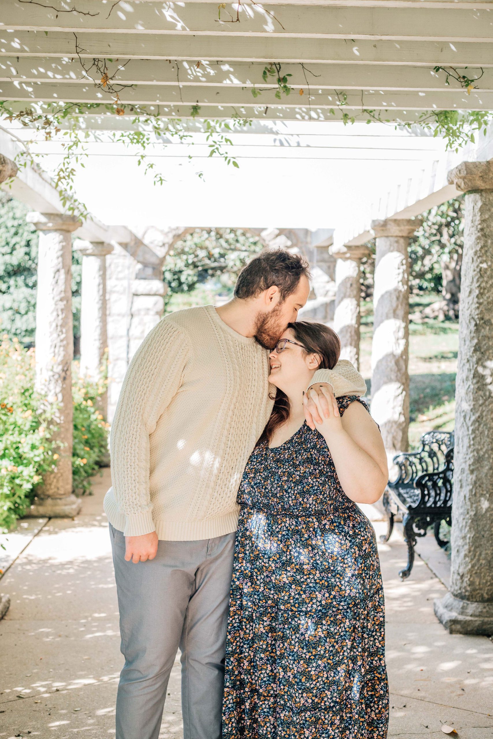 man leaning into his fiance as he kisses her foreheads and she smiles while for natural engagement photo idea