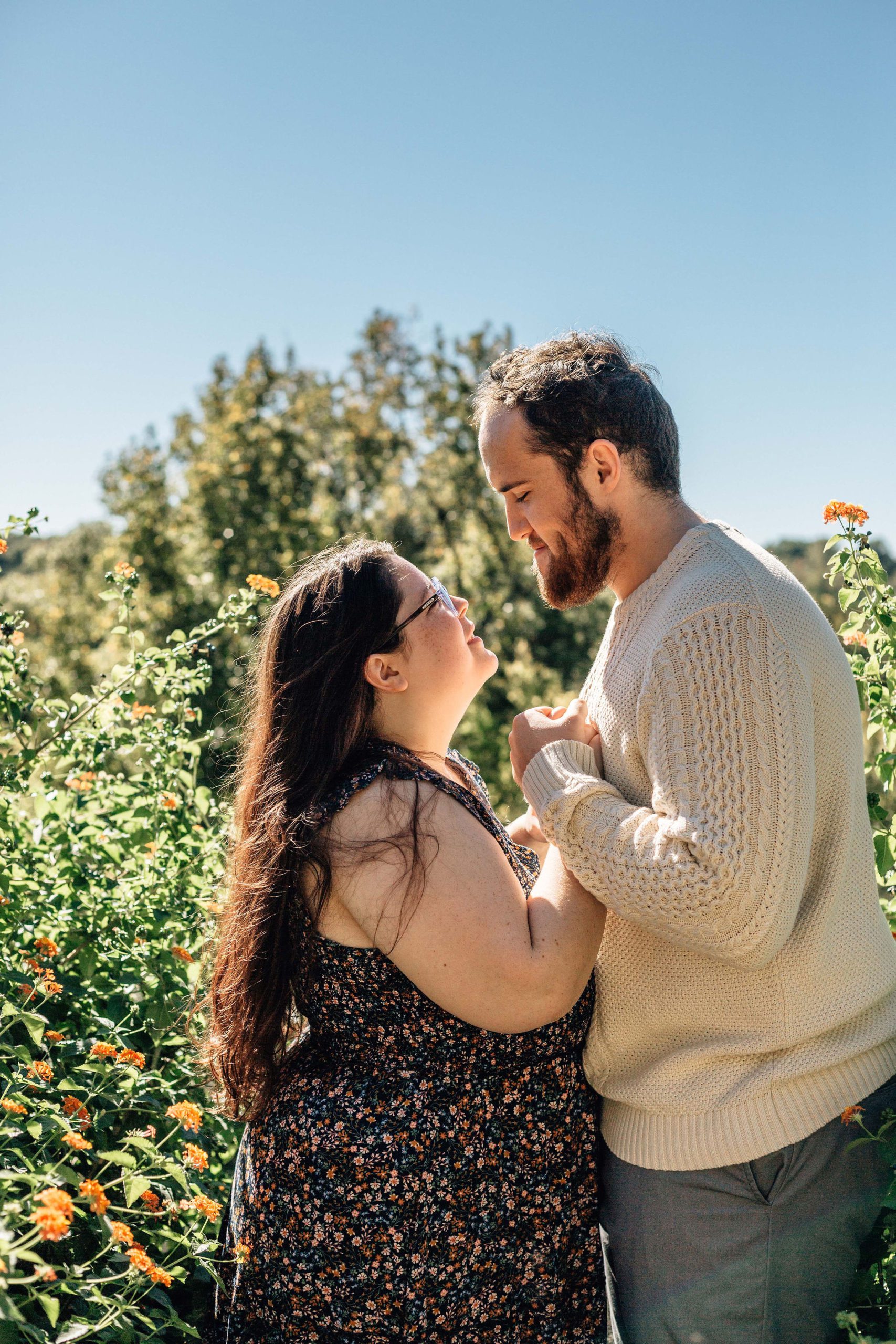 Hampton Roads natural engagement photo pose ideas with man and woman in a garden of flowers holding hands and facing each other