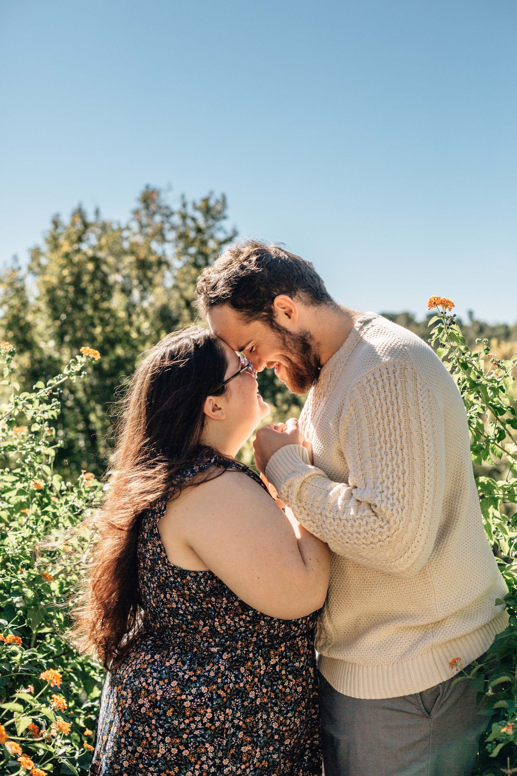 natural engagement photo pose of man and woman holding hands and facing each other as they hold their foreheads together