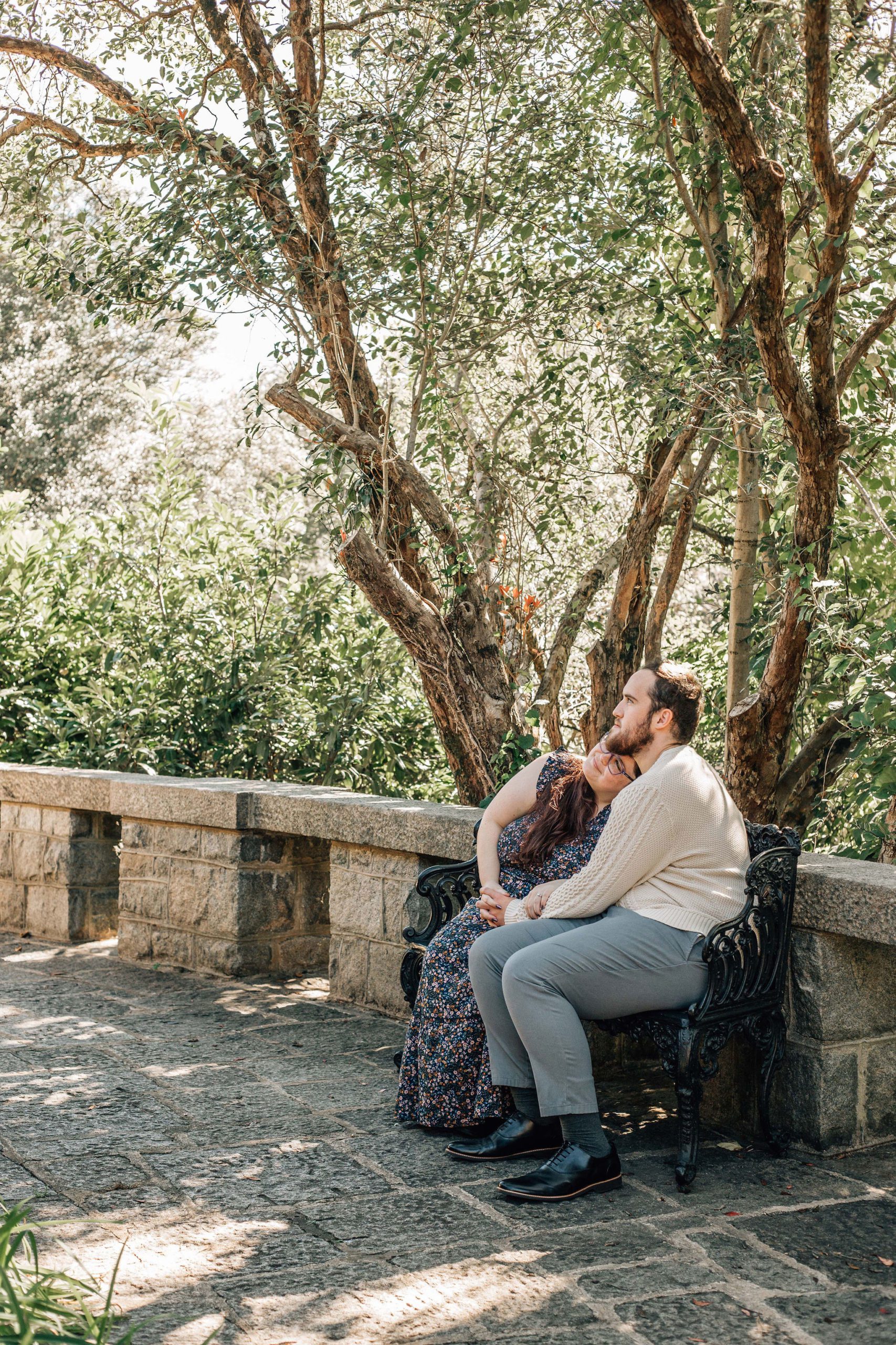 natural engagement photo pose ideas of Couple sitting together on a bench having a quiet moment looking off together thinking about their Maymont Wedding Venue plans