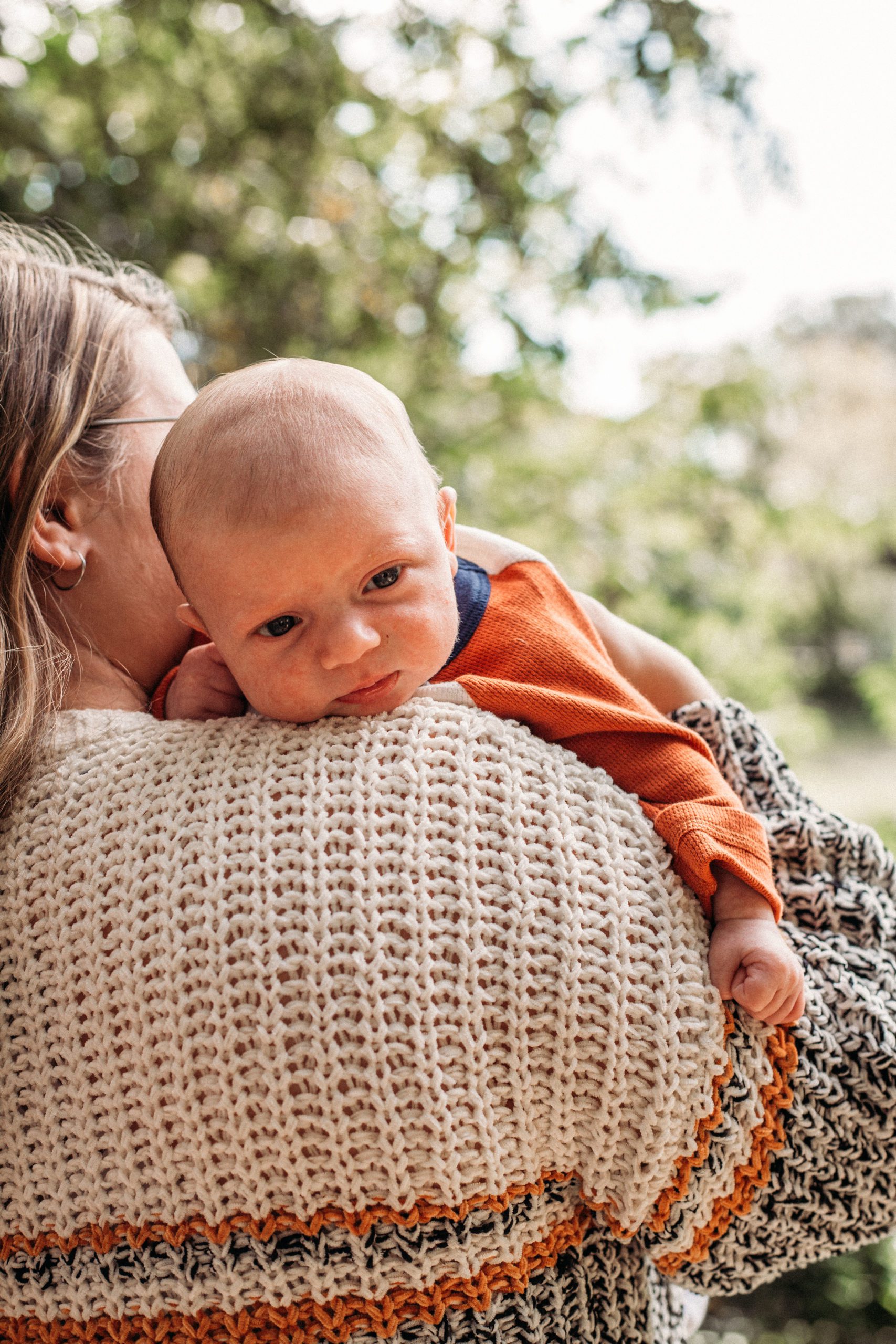 newborn baby boy resting his head on a woman shoulder for an outdoor Hampton Roads family photoshoot
