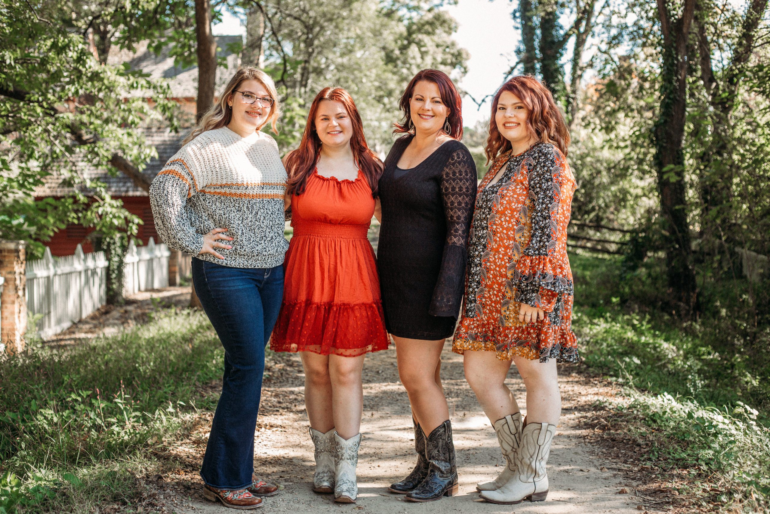 mother and her three daughters hugging each other on a dirt road in Williamsburg during their Hampton Roads family photographer