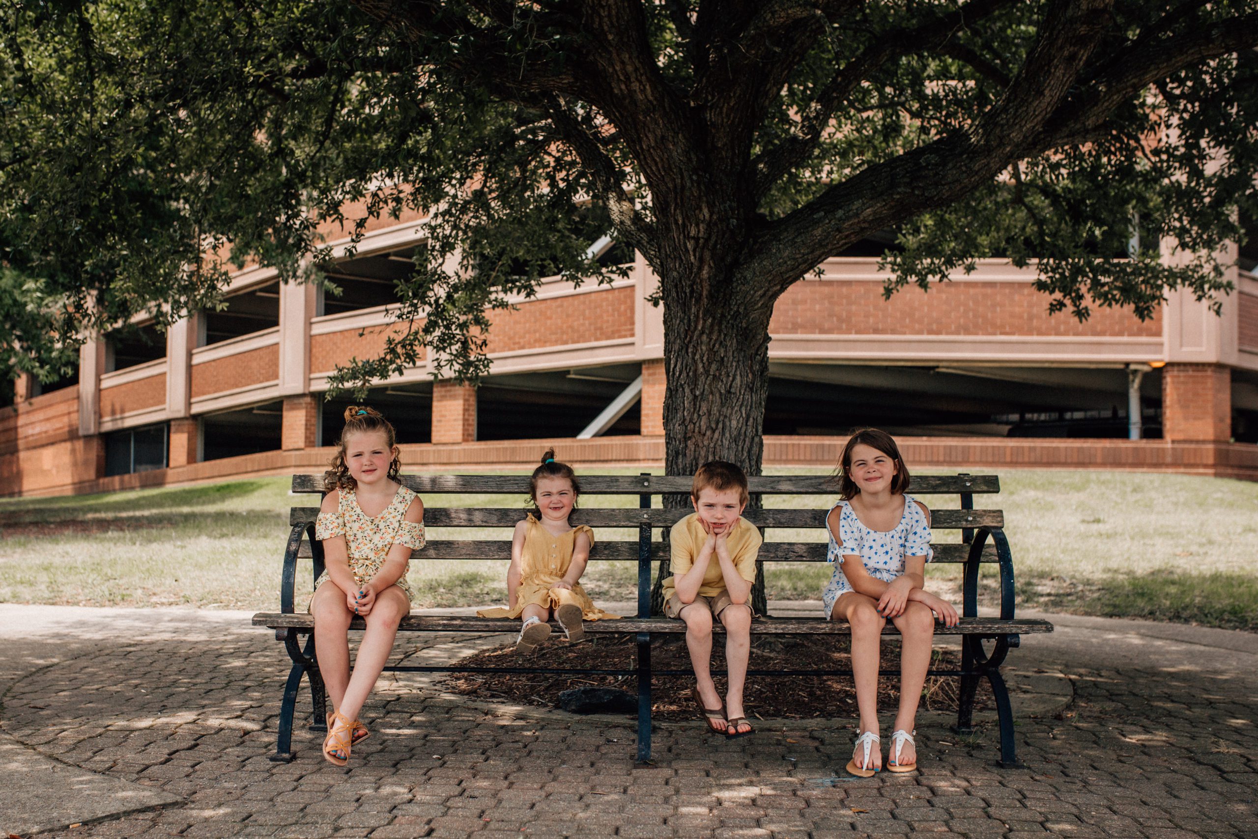 four young children sitting on a bench in Hampton Roads for their family photos