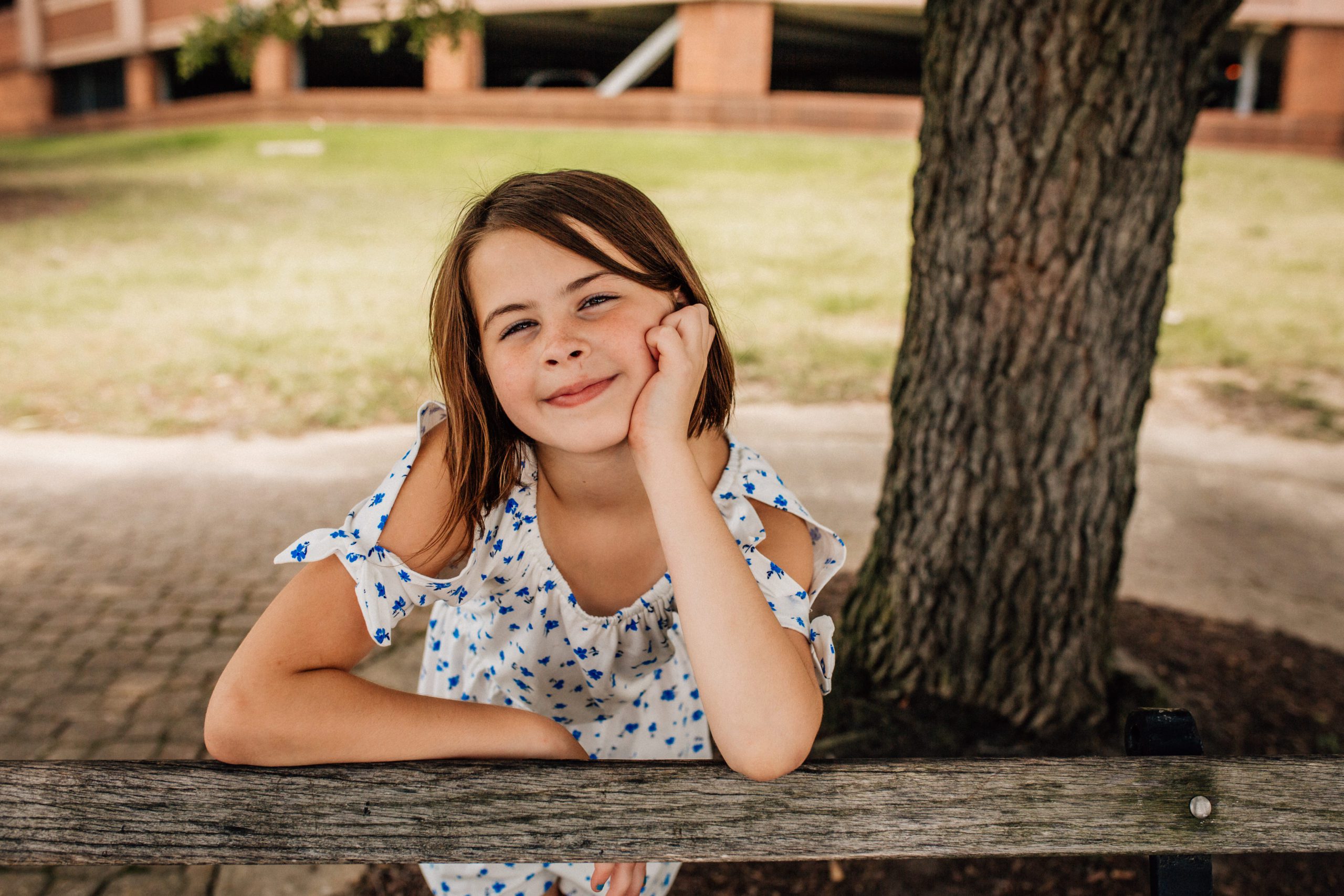 child posing with her hand on her cheek and her arm on a bench captured by Hampton Roads family photographer
