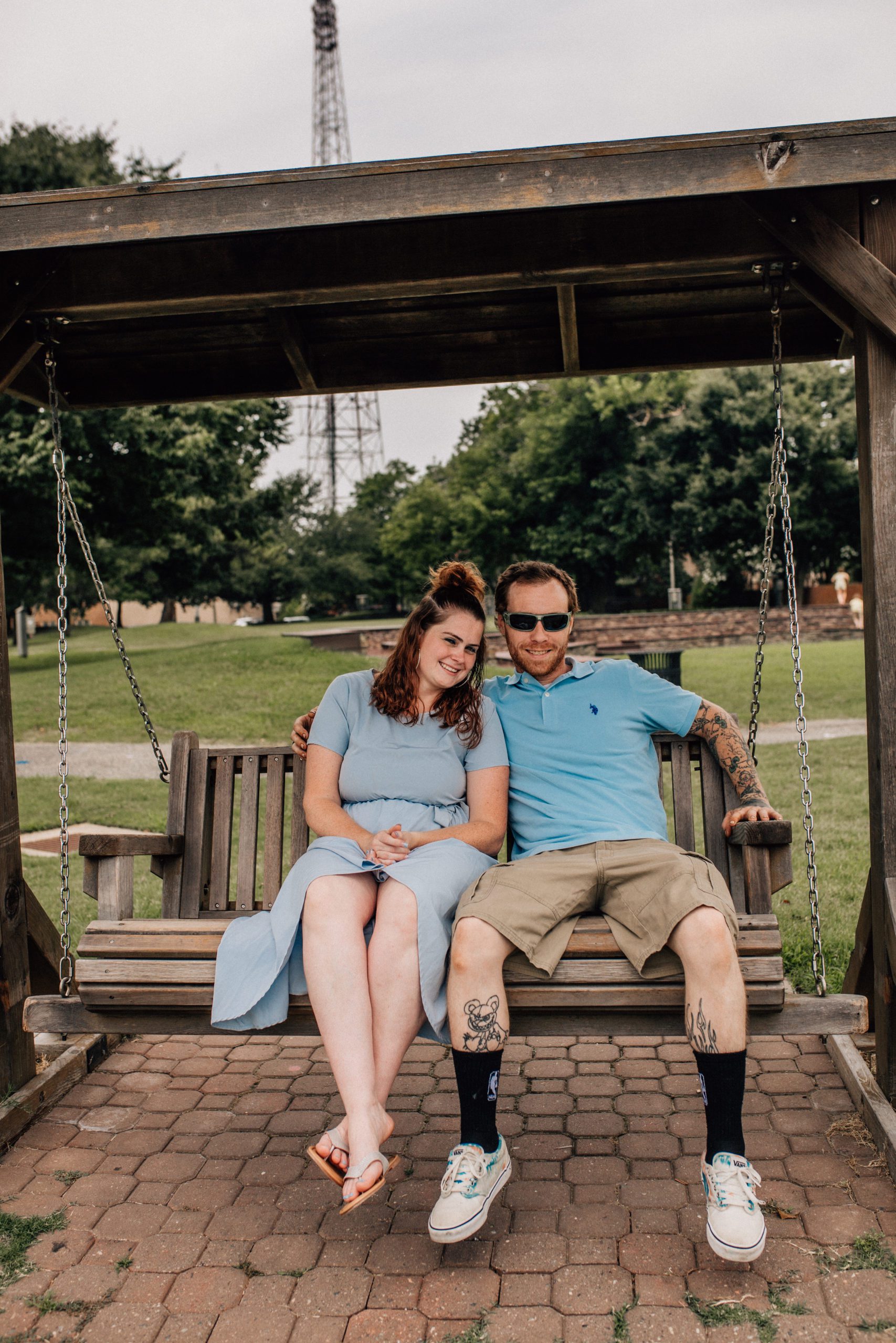 mom and dad sitting on a wooden swing together for their Hampton Roads family photos with young children 