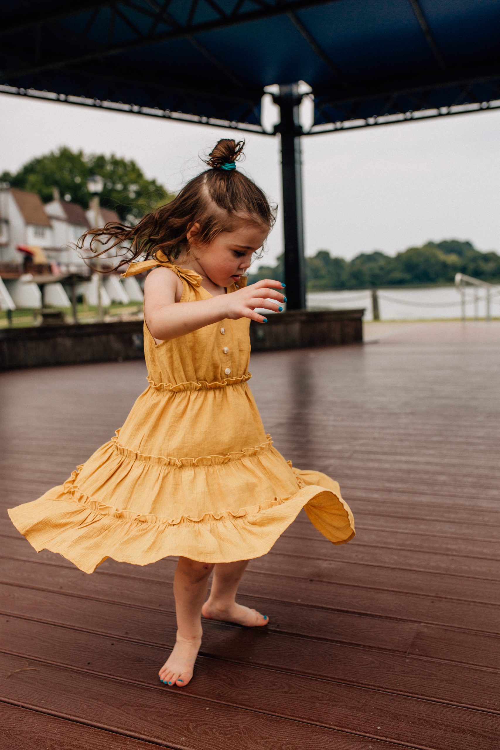 little girl dancing in a yellow dress under a terrace for Hampton Roads family photography