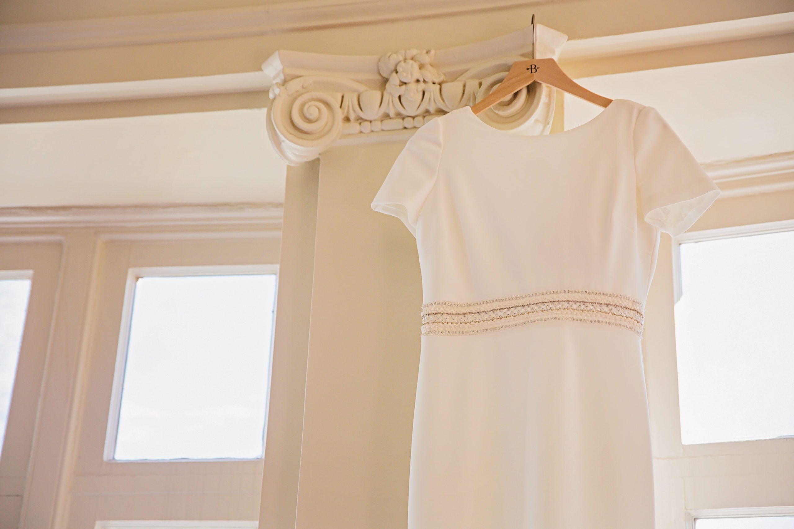 Virginia wedding venue detail shot of wedding dress hanging on the crown molding of the bridal suite