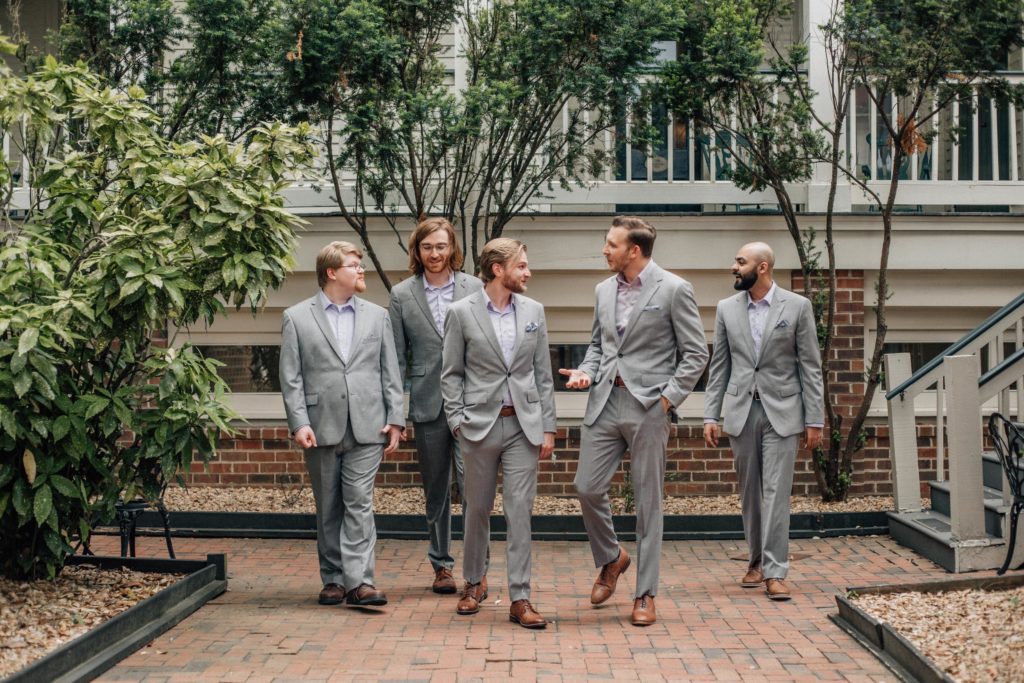 Image of the courtyard in one of the best wedding venues in Richmond, Virginia where the groomsmen are walking and talking while looking at each other prior to the ceremony.