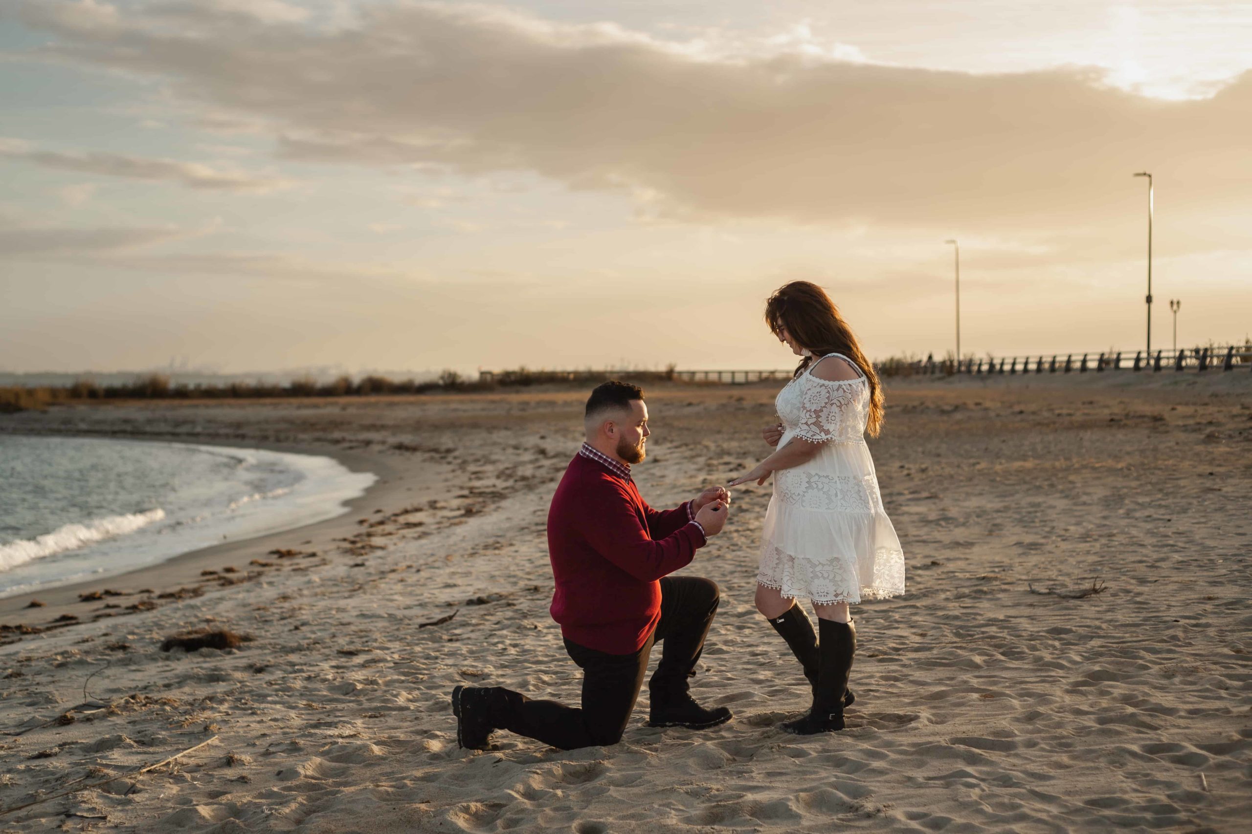 man proposing to his girlfriend on the beach at fort monroe during sunset which is one of the best places to propose in virginia